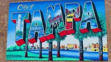 Un mural con las palabras "City of Tampa" y una representación del horizonte de la ciudad, incluyendo un faro y palmeras.