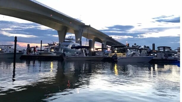 Un port de plaisance où des bateaux sont amarrés sous un pont.
