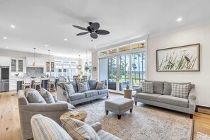 A spacious living area with a grey sofa set, a coffee table, and a ceiling fan.