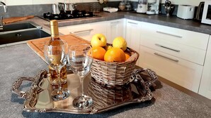 Un comptoir de cuisine sur lequel est posé un plateau décoratif contenant une bouteille de spiritueux, deux verres et un panier d’oranges.