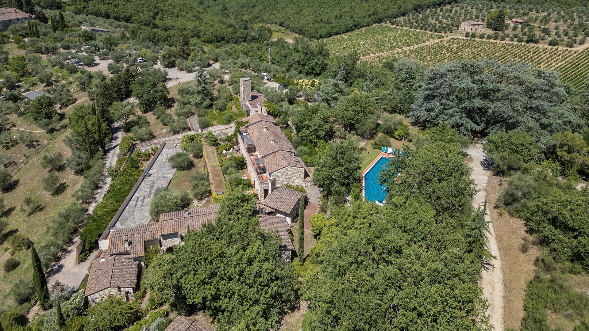 Luchtbeeld van een woongebied met meerdere gebouwen, een zwembad en veel groen eromheen.