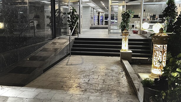 Moderni aula, jossa on marmorilattia, portaikko ja lasinen sisäänkäynti, joka johtaa valoisiin sisätiloihin.