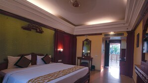 A hotel room with a large bed, a desk, a mirror, and a door leading to a balcony. - NRS Royal Palace (Brahmagiri)