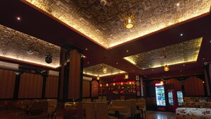 A restaurant with wooden flooring, tables, and chairs. There is a bar area with a Coca-Cola refrigerator. - NRS Royal Palace (Brahmagiri)