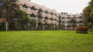 A hotel with multiple balconies, a central courtyard, and palm trees. - NRS Royal Palace (Brahmagiri)