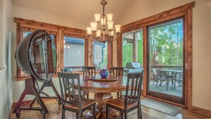 A dining area with a round wooden table, six chairs, a chandelier, and large windows offering a view of the outdoors. - BIG downtown home w/ views and great amenities! (Breckenridge)