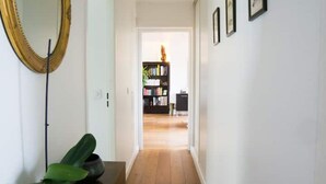 A hallway with a wooden floor, a large mirror on the left, and a bookshelf in the background. - ★ Beautiful Rooftop between Paris and Versailles ★ (Chaville)