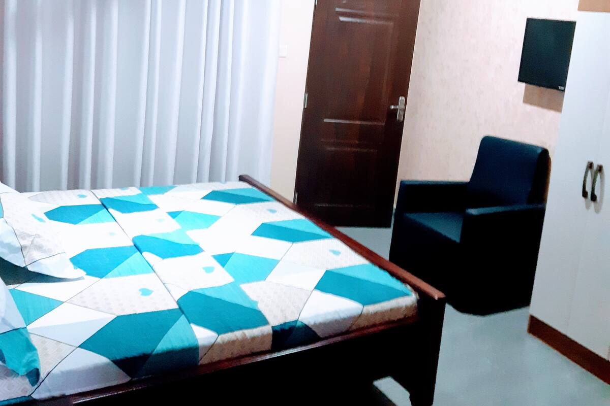 Un dormitorio con cama, una silla, un armario, una puerta y un ventilador de techo.