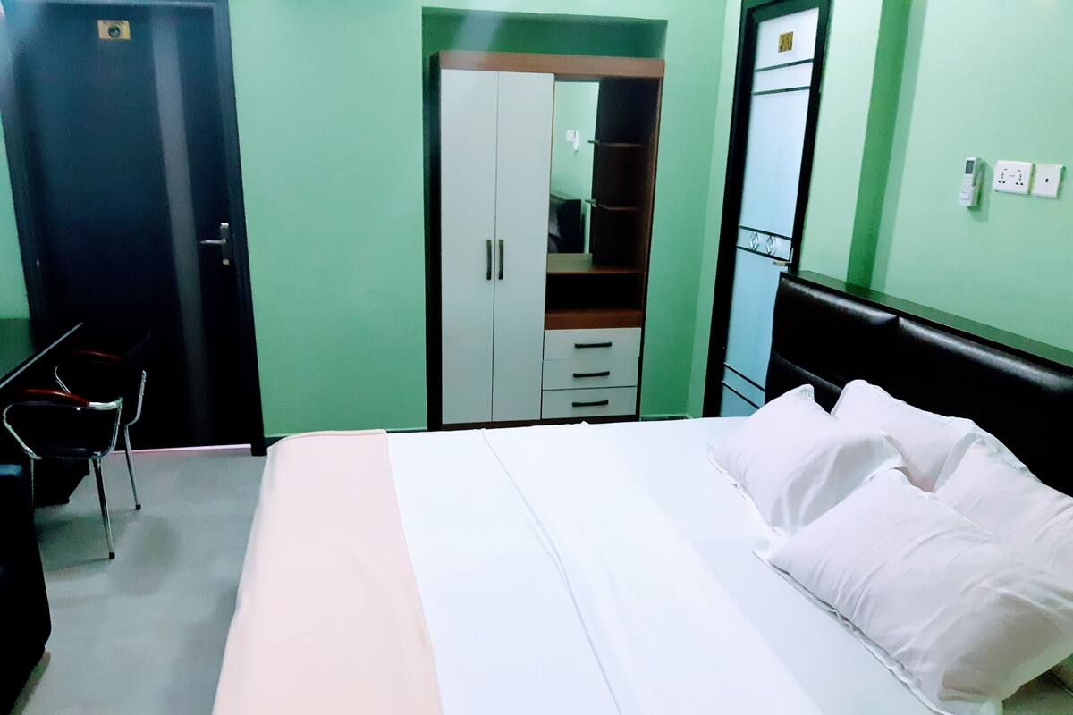 Un dormitorio con cama, escritorio, silla, armario y espejo.