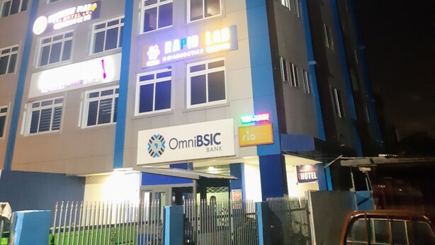 Un edificio de varios pisos con carteles para OmniBSIC Bank, Rapid Lab Diagnostic y un hotel.