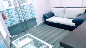 Una habitación con una mesa de vidrio, un sofá azul y blanco y una pared con diseño de ladrillo.