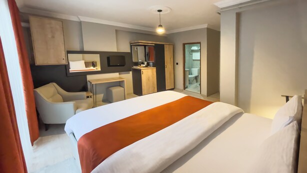 A hotel room with a bed, a desk, a chair, a television, and a bathroom visible through an open door. - NEPTÜN INN (Kirklareli)