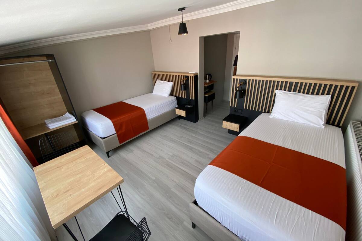 Una habitación de hotel con dos camas, un escritorio, una silla y un espejo.