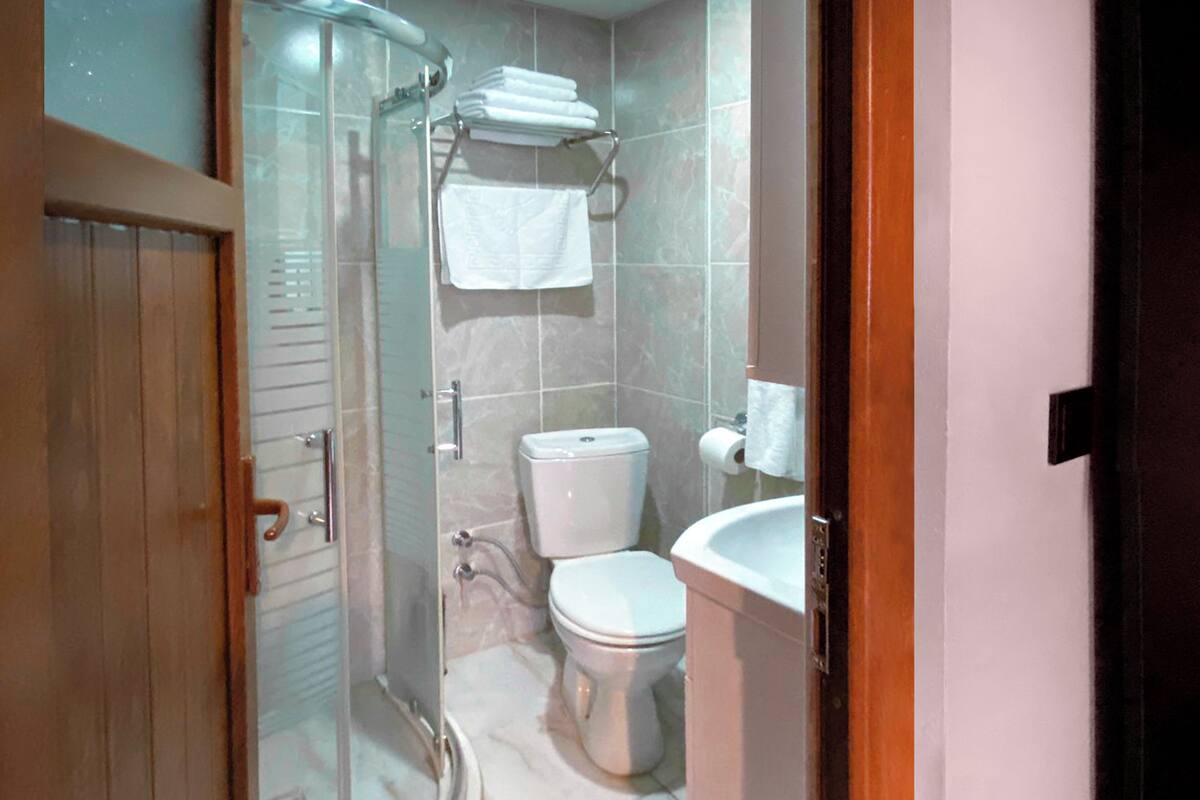 Un baño con cabina de ducha de vidrio, inodoro y lavamanos.