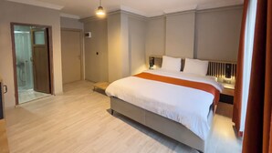 A modern hotel room with a large bed, a bedside table, a chair, and a bathroom visible through an open door. - NEPTÜN INN (Kirklareli)