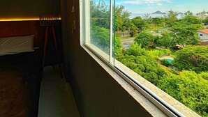 A room with a large window overlooking a lush landscape with a pool and greenery.