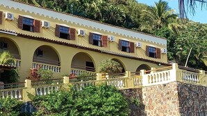 A two-story building with arched windows and a balcony, surrounded by lush greenery. - colonial hotel de ilhabela (Ilhabela)
