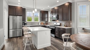 A modern kitchen with a central island, stainless steel appliances, and dark wood cabinetry. - Seabrook Hidden Treasure | Pirate Theme, Hot Tub | 4BR, Sleeps 11, EV Charger (Pacific Beach)