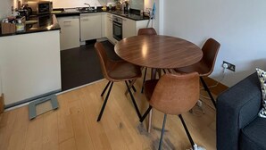 Cozinha compacta com armários brancos, uma ilha central e um espaço de refeições com uma mesa redonda e quatro cadeiras.