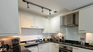 Uma cozinha moderna com armários brancos, bancada preta e eletrodomésticos de aço inoxidável.