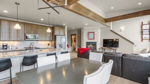 A spacious living area with a dining table, sofas, and a fireplace.