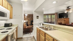 A kitchen with wooden cabinets, a microwave, a stove, a sink, and a ceiling fan. - Walk to the Marina and Amph in this central 2 BR Condo! (Dillon)