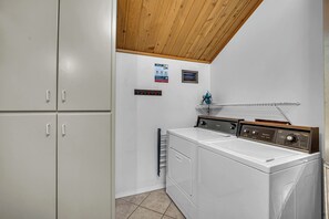 A laundry room with a white washing machine, a dryer, and a wooden ceiling.