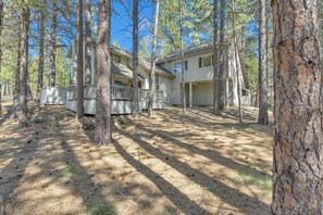 A two-story house surrounded by tall pine trees.