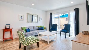 A living room with a sofa, a patterned armchair, a coffee table, and a small table with a sign.