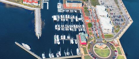 An aerial view of a marina with multiple docks, a roundabout, and surrounding buildings.