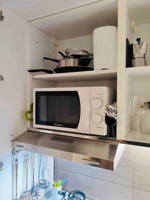 Une cuisine équipée d’un four à micro-ondes, d’une casserole sur la cuisinière et de divers ustensiles sur le plan de travail.