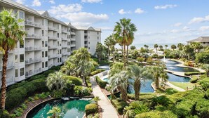 Resort com várias piscinas, palmeiras e vista para a praia.