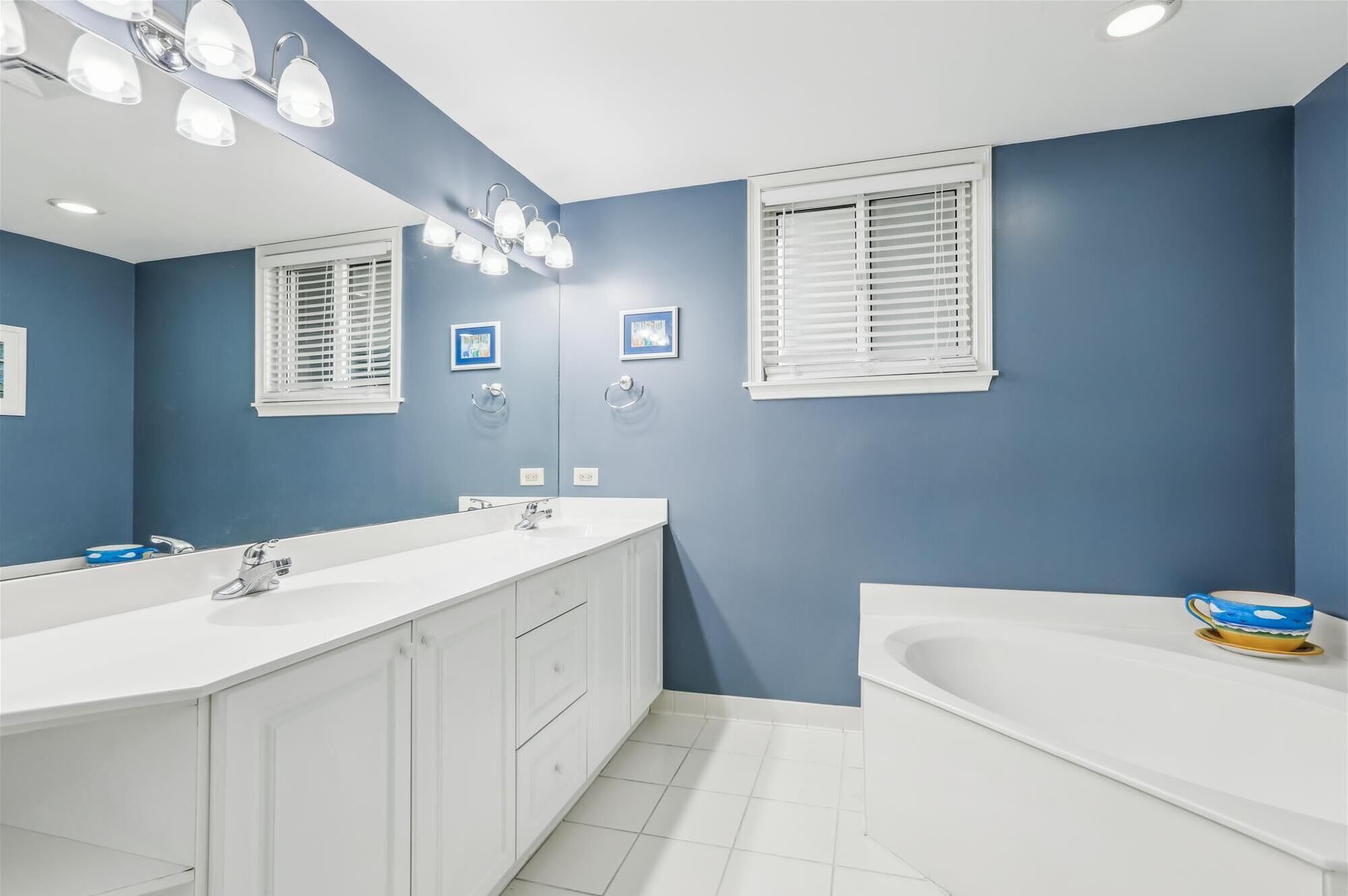 A bathroom with a double sink vanity, a bathtub, and a large mirror.
