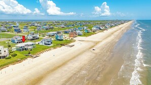 An aerial view of a coastal residential area with houses, a beach, and a pier. - Beachfront w/ Huge Deck, Dog Friendly, Dune Walkover, Feel Right at Home! (Galveston)