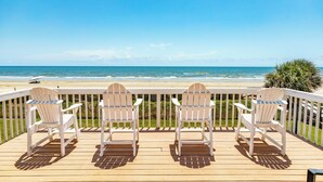 A wooden deck with three white Adirondack chairs facing a beach. - Beachfront w/ Huge Deck, Dog Friendly, Dune Walkover, Feel Right at Home! (Galveston)