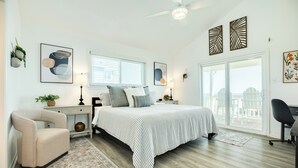 A bedroom with a bed, a chair, a desk, a window, and a balcony. - Beachfront w/ Huge Deck, Dog Friendly, Dune Walkover, Feel Right at Home! (Galveston)
