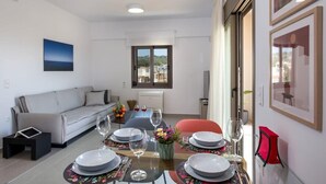 A dining area with a table set for four, a sofa, and a window with a view.