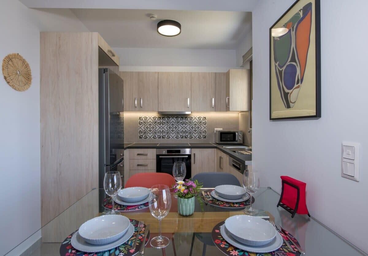 A modern kitchen with wooden cabinets, a microwave, and a patterned backsplash.