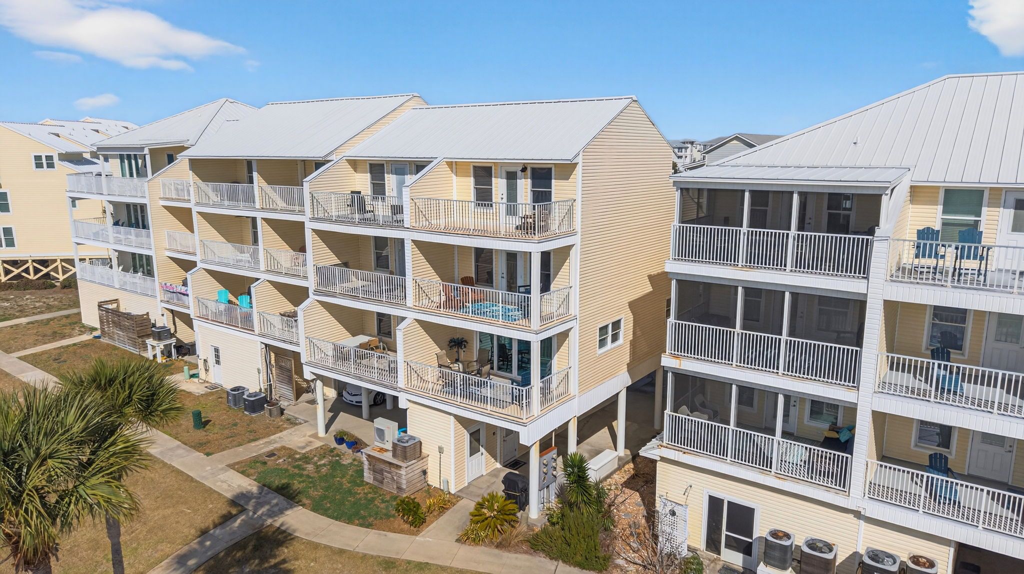 A multi-story residential building with balconies, a pool, and a well-maintained lawn.