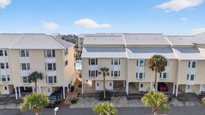 A row of multi-story buildings with a central courtyard, featuring a swimming pool and palm trees. - Community Pool, 3bdrm (Cape San Blas)