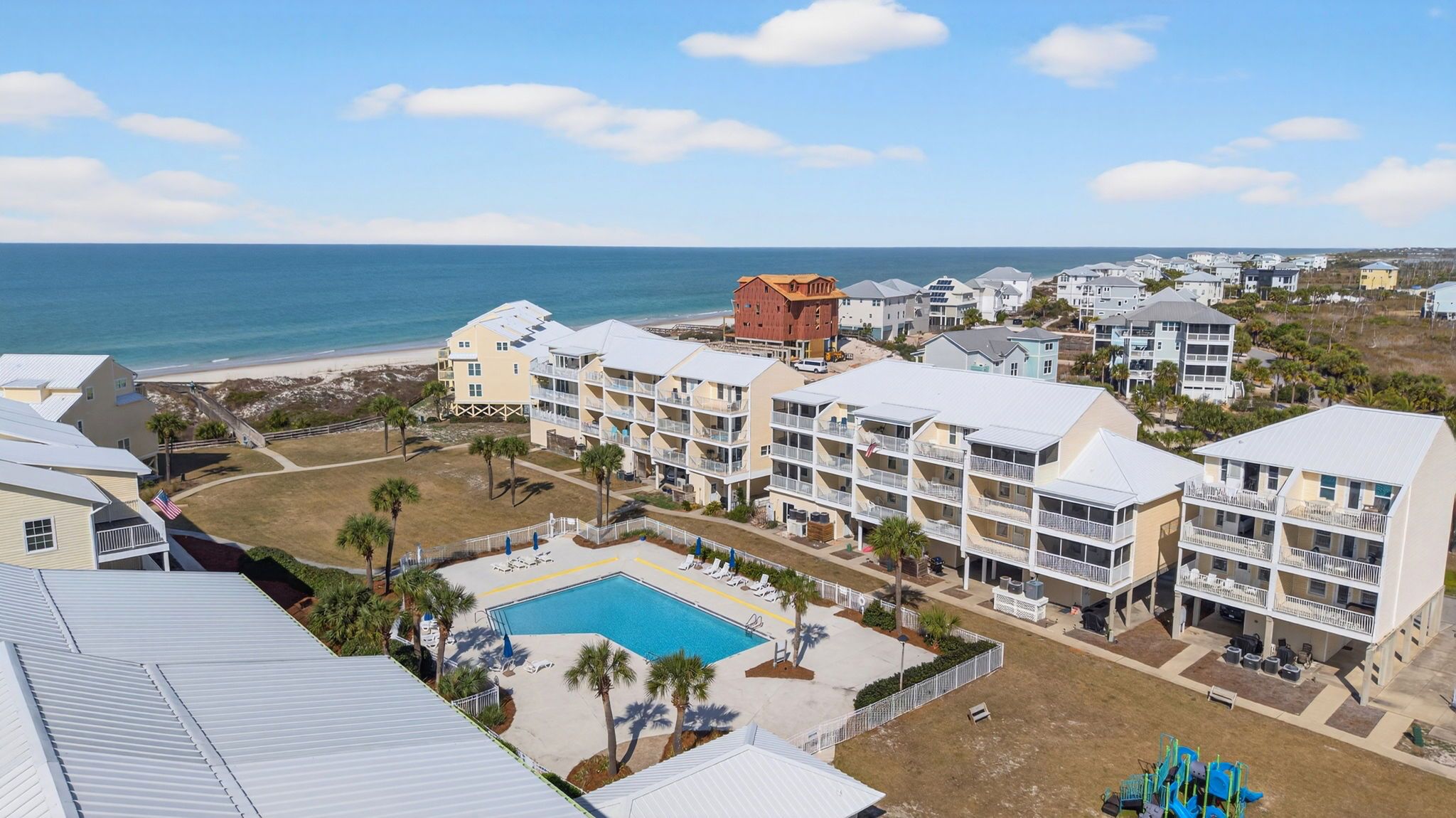 Ein Hotel an der Küste mit mehrstöckigen Gebäuden, einem Swimmingpool und Blick auf den Strand.