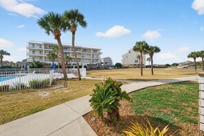 A hotel with a pool, palm trees, and a grassy area. - Community Pool, 3bdrm (Cape San Blas)