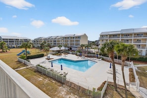 A hotel with multiple balconies, a swimming pool, and a playground. - Community Pool, 3bdrm (Cape San Blas)