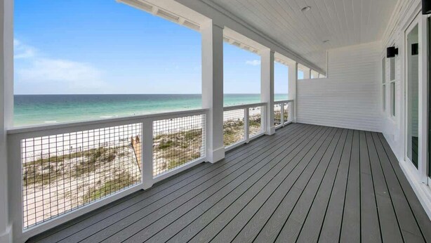 A covered porch with a view of the ocean and beach.