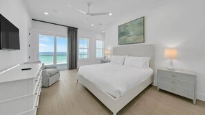 A modern bedroom with a large bed, a desk, a chair, and a nightstand.