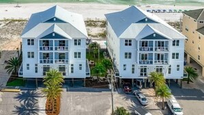 Two beachfront buildings with balconies, a parking area, and a view of the ocean.