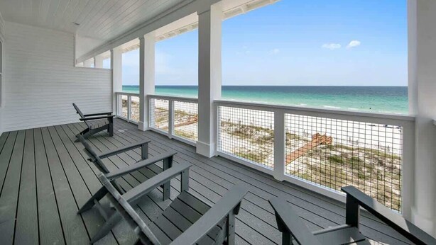 A covered deck with a view of the beach and ocean.