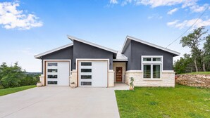 Une maison moderne à deux étages, dotée d’un garage, d’une porte d’entrée et de fondations en pierre.