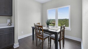 Un espace repas comprenant une table, des chaises et une fenêtre donnant sur un paysage agréable.