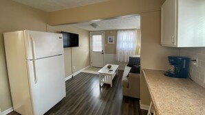 A compact kitchen with a refrigerator, a coffee maker, and a television mounted on the wall. - Cozy cottage for a couple's weekend get away! (Russells Point)